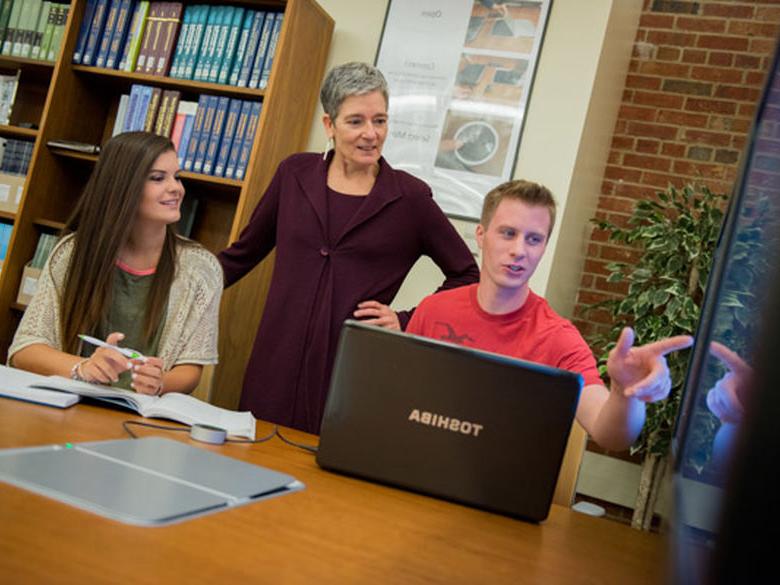 Two students share their research with a faculty member